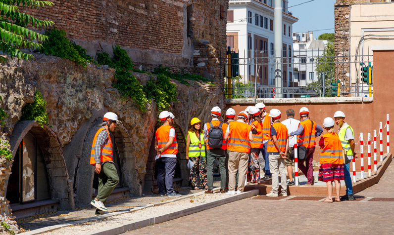 Gruppo di persone con caschi e giubbotti riflettenti in visita tecnica